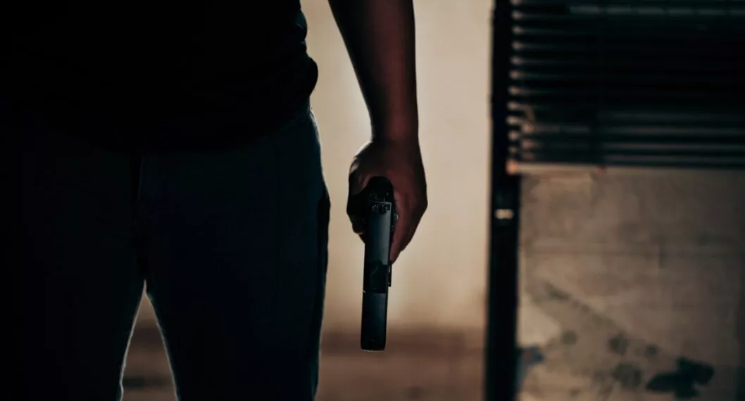 A black-shirted culprit with a gun breaks through the door of robber concept.