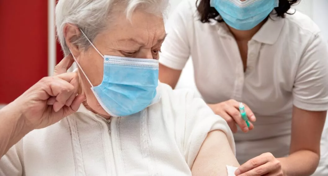 senior adult elderly woman with grey hair is receiving a vaccination against covid, concept pandemic coronavirus protection or flu
