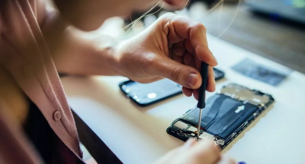 Imagen de una persona arreglando un celular a propósito de que Apple sacó servicio que le enseña cómo reparar un iPhone al usuario
