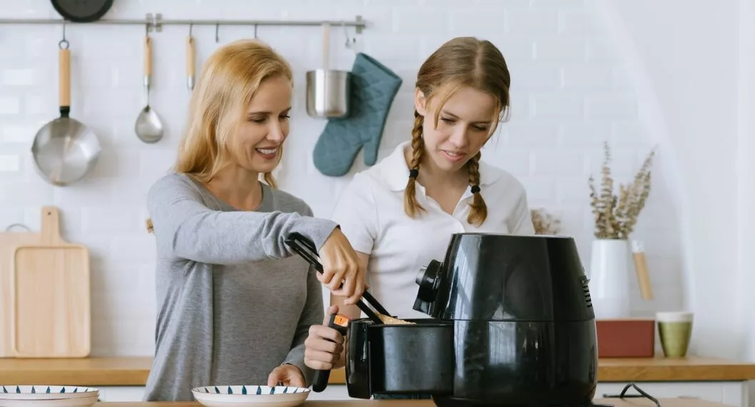 Mujeres utilizando la 'Air fryer' ilustran nota de cuánta luz consume la olla
