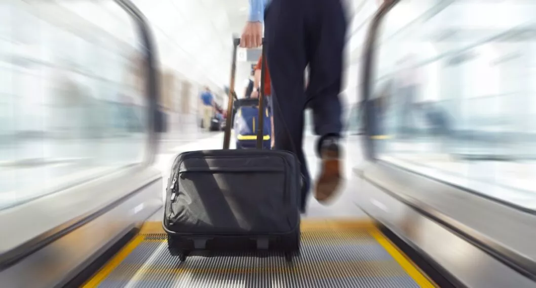 business man travels up escalator with latop briefcase travel bag in airport or office