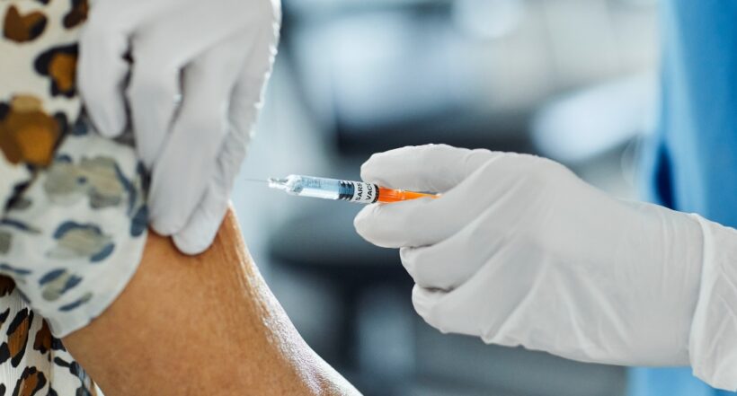 Cropped image of nurse injecting patient. Female healthcare worker is working at hospital. She is holding syringe.