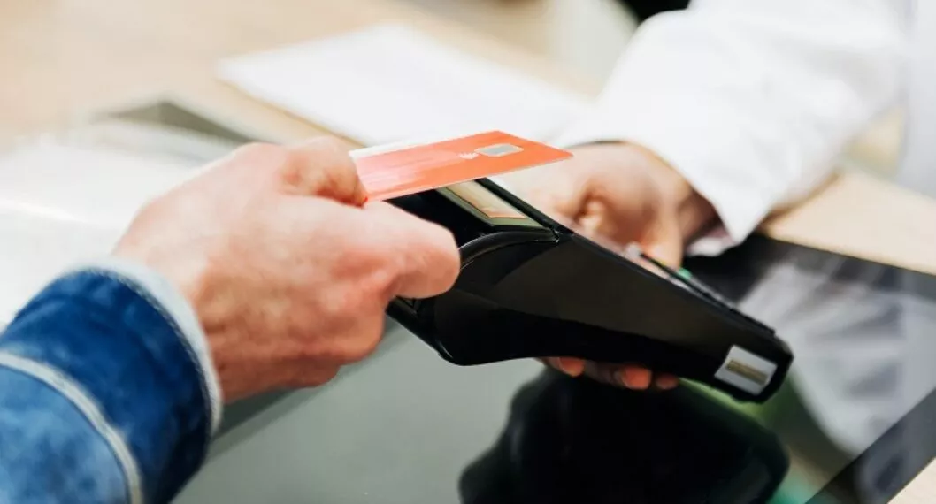 Persona pagando con tarjeta ilustra nota sobre requisitos para sacar tarjeta de crédito en Colombia
