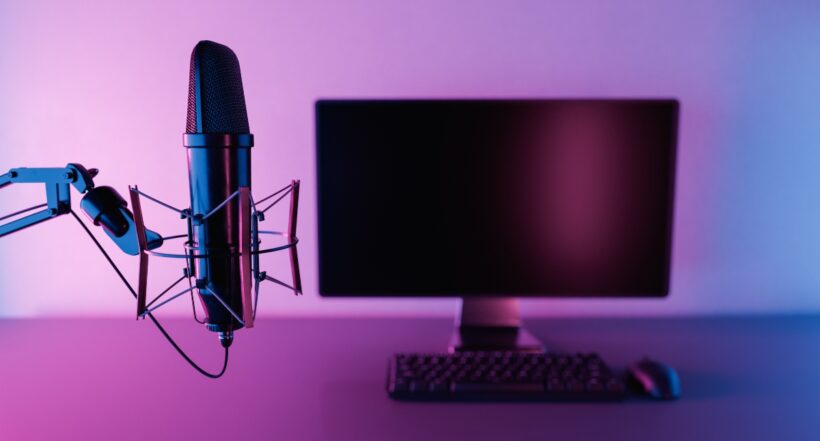 close up of studio microphone with out of focus pc monitor with neon lighting. concept of podcast, recording and streaming studio. 3d render