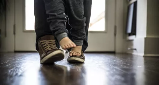 Toddler boy (2 yrs) walking on father's feet, closeup