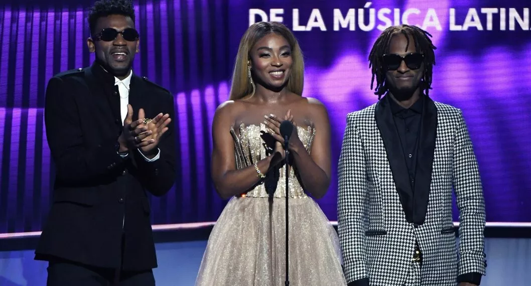 LAS VEGAS, NEVADA - APRIL 25:  (L-R) Carlos "Tostao" Valencia, Gloria "Goyo" Martinez and Miguel "Slow" Martinez of ChocQuibTown present an award during the 2019 Billboard Latin Music Awards at the Mandalay Bay Events Center on April 25, 2019 in Las Vegas, Nevada.  (Photo by Ethan Miller/Getty Images)