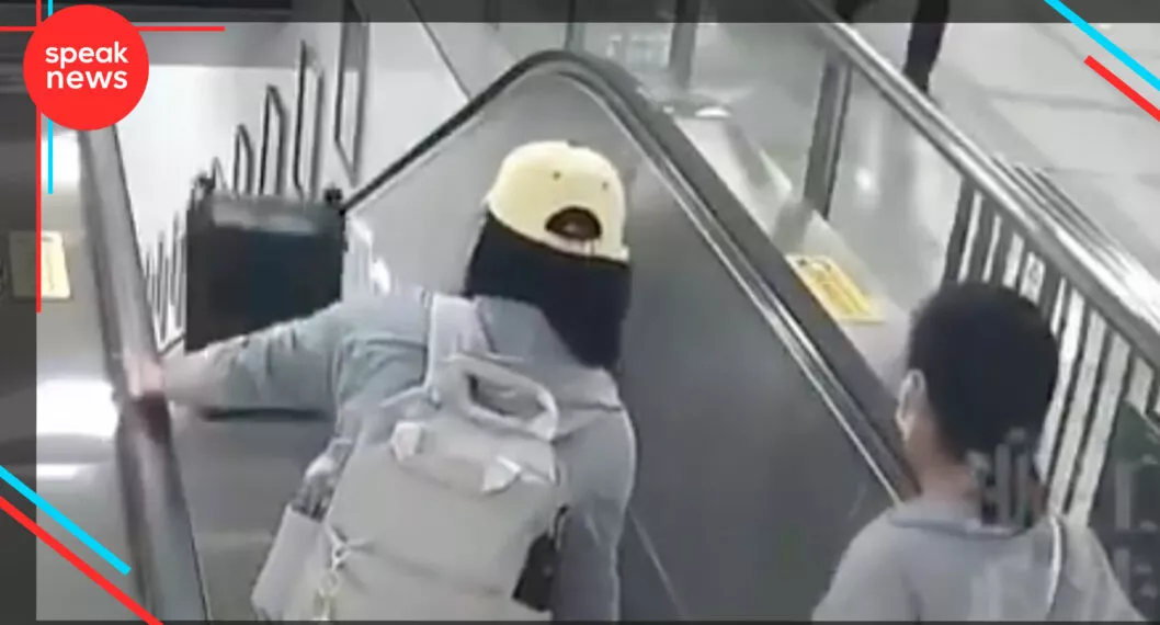 Imagen de la joven que pone su maleta de viaje en escaleras eléctricas y causa un accidente