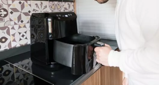 Hombre usando la 'Air Fryer' ilustra nota sobre cosas que no se pueden introducir en esa olla