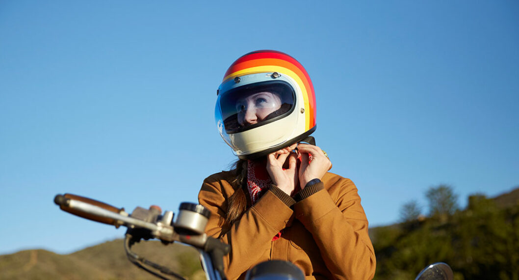 Mujer colocándose un casco. Nota sobre las mejores motocicletas para principiantes.