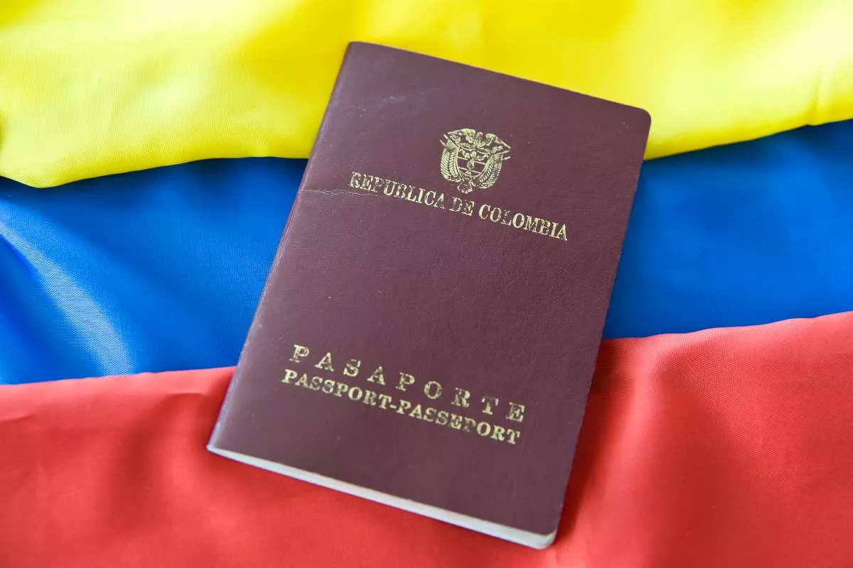 Foto del pasaporte colombiano junto con la bandera del país.