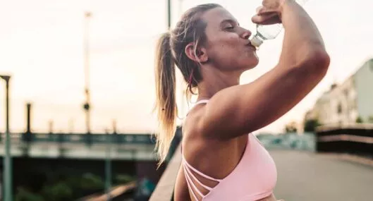 Mujer bebiendo agua después de hacer ejercicio