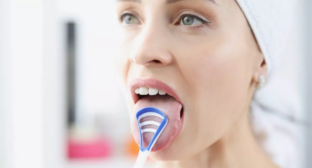 Mujer se cepilla dientes, a propósito de por qué se debe cepillar la lengua y cómo hacerlo.