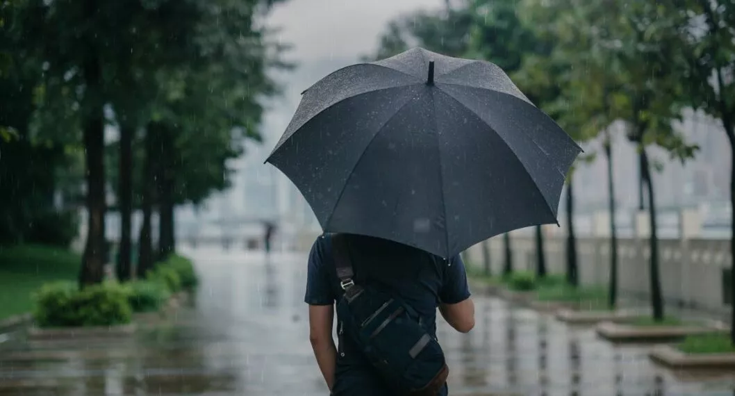 Imagen de alguien con una sombrilla por lluvias