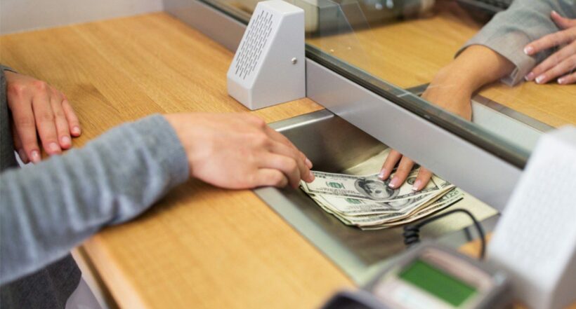 Imagen de alguien recibiendo dólares de un banco
