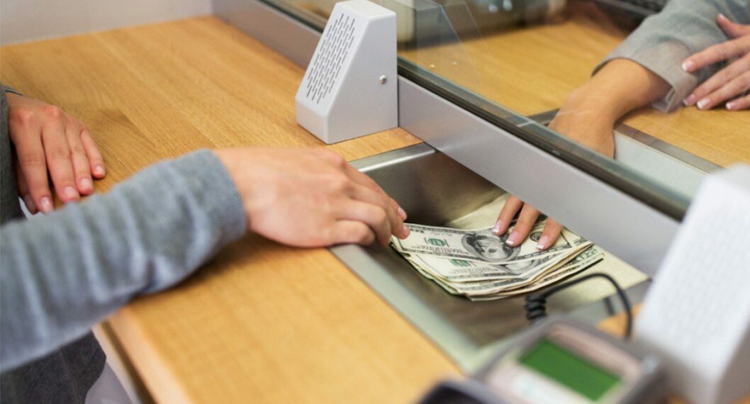 Imagen de alguien recibiendo dólares de un banco