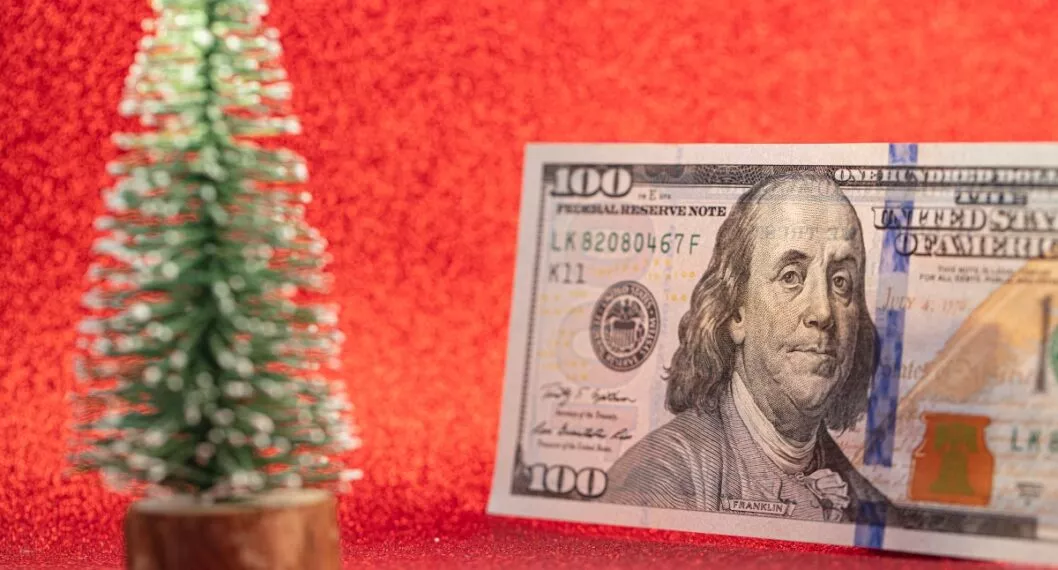 100 dollar bill and toy fir tree on red background for design purpose