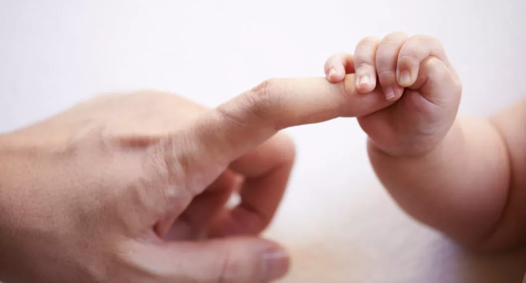 Foto de la mano de un recién nacido a propósito de nacimiento de bebé el mismo día que su papá y mamá