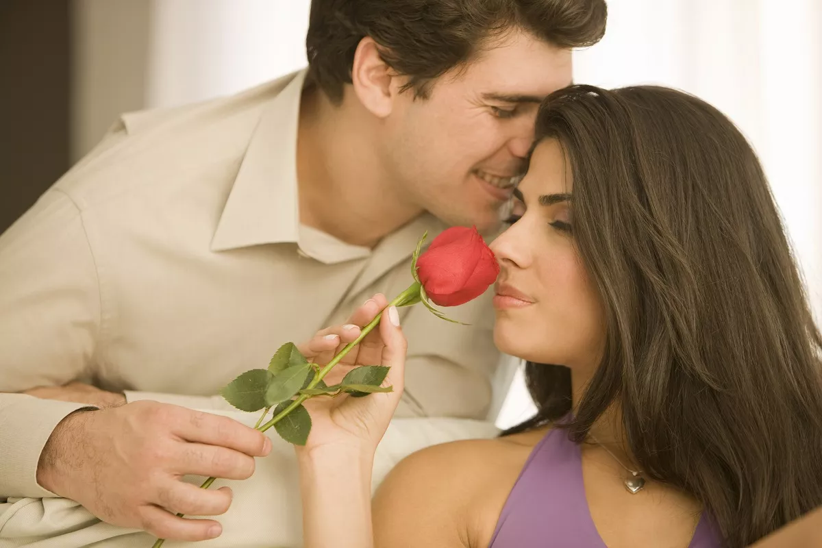 Man giving woman a red rose. Woman smelling rose.