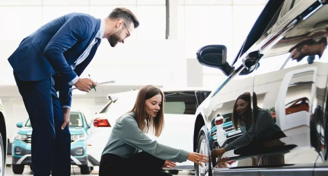 Un hombre y una mujer revisando un carro a propósito de las recomendaciones que se deben tener en cuenta al momento de comprar un carro usado.