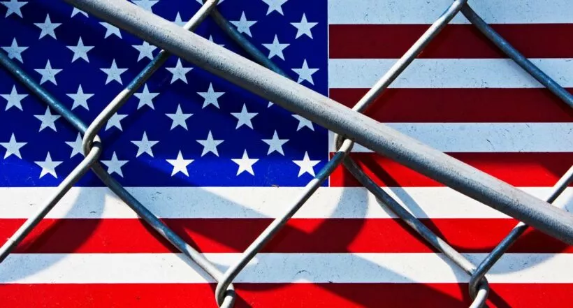 Foto de contexto de bandera de EE. UU. con rejas, a propósito de aplicación CBP One para migrantes que solicitan asilo