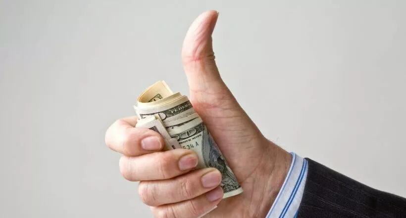 Foto de contexto de mano con dólares a propósito de temporada de impuestos EE. UU. 2023