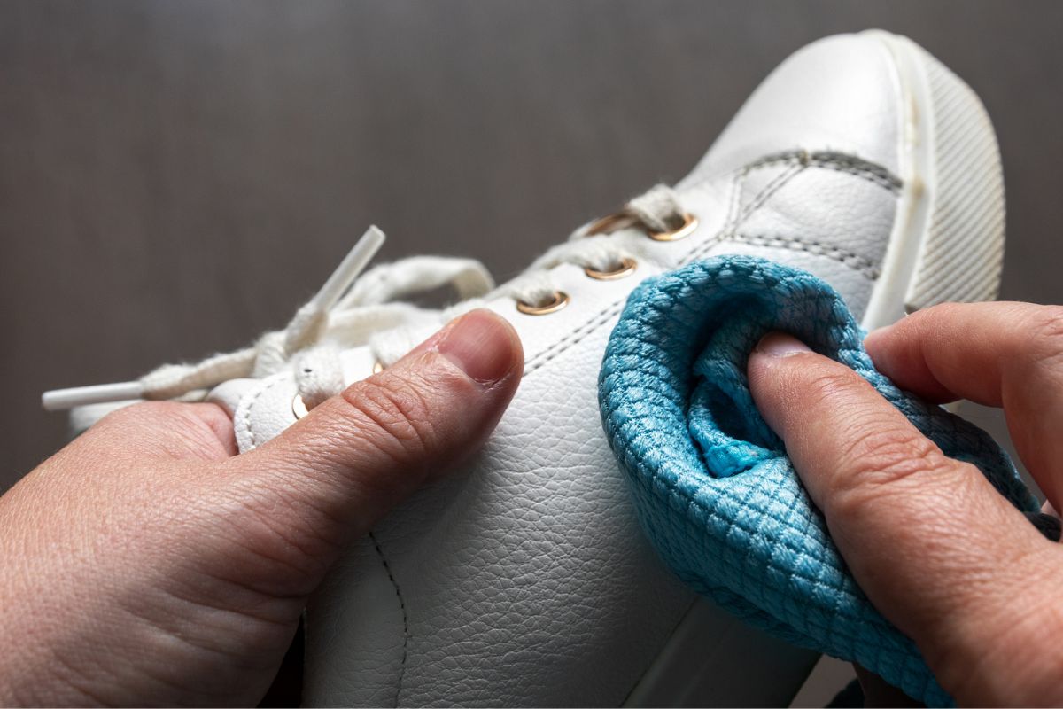 Persona blanqueando los zapatos a propósito de cómo devolverles el color blanco usando solo un producto.