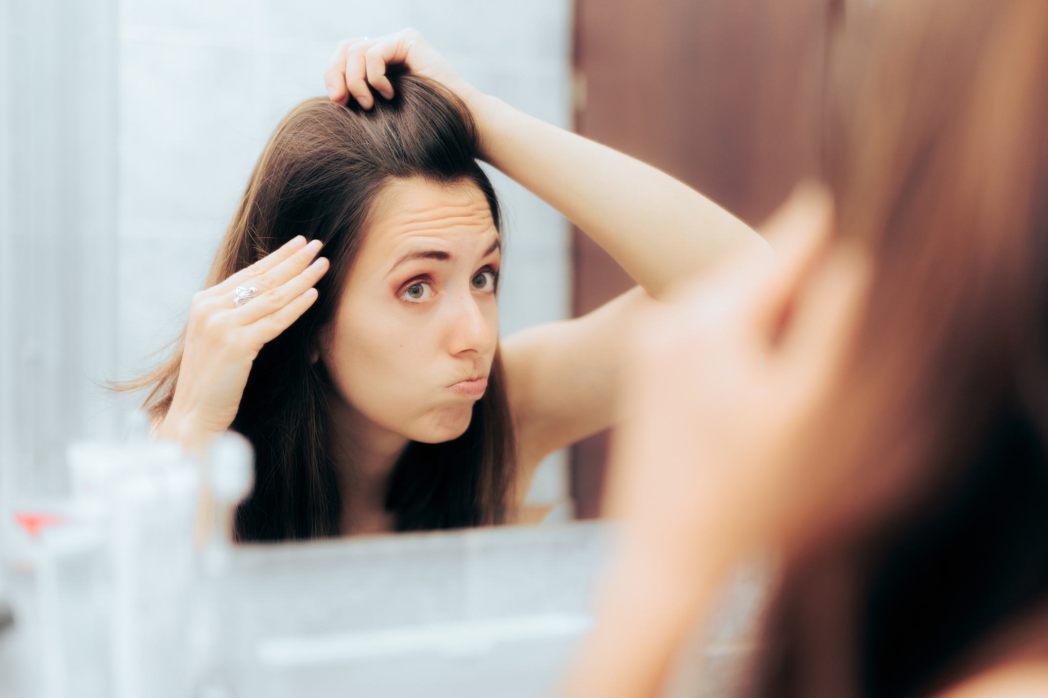 Mujer mirándose al espejo las canas. En relación con prevención.
