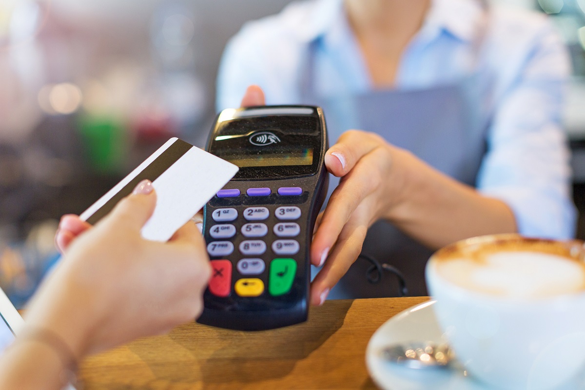 Mujer pagando con tarjeta de crédito, en nota sobre plásticos que dan puntos para comprar ropa y hasta viajes