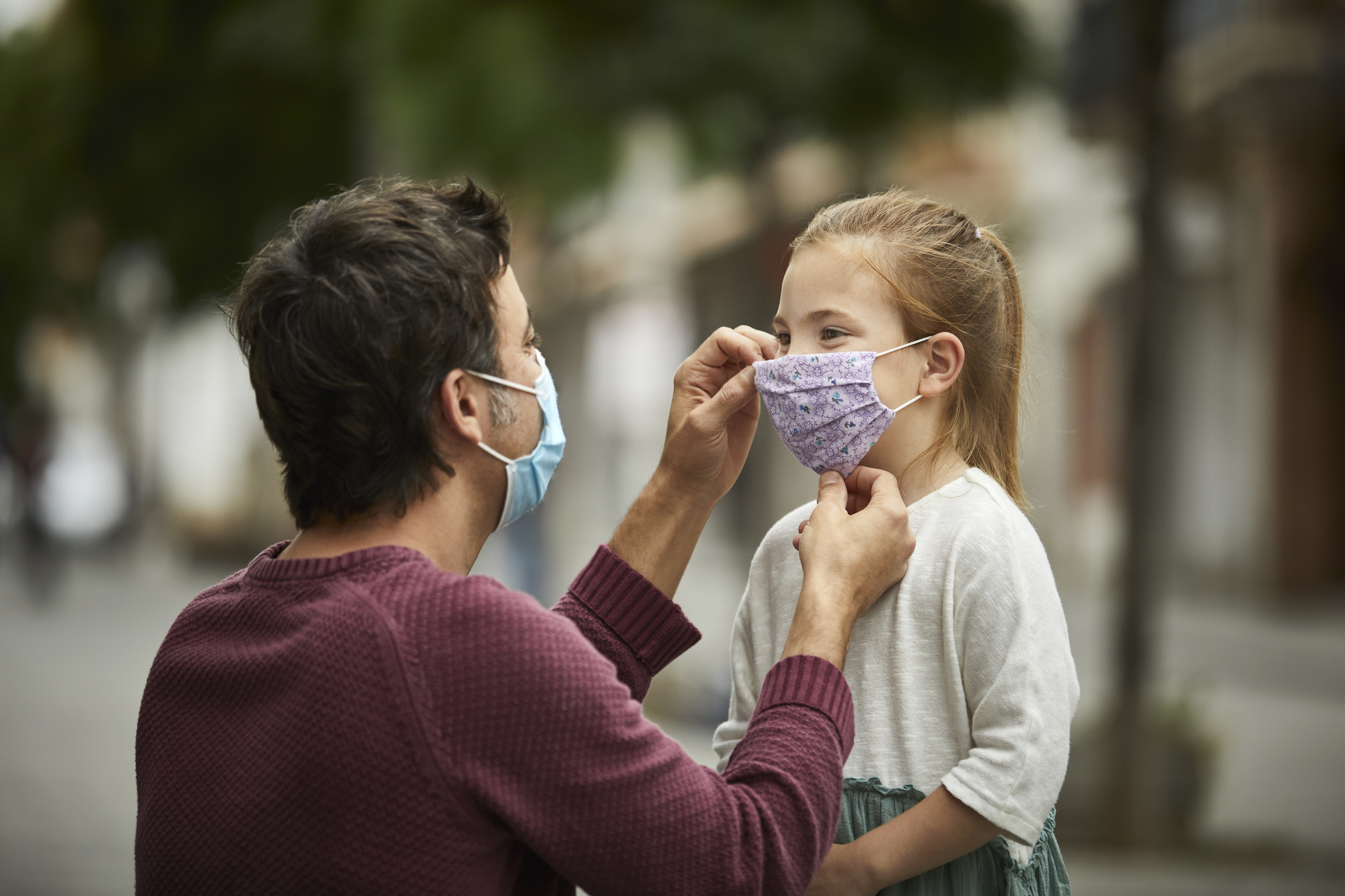 Padre poniendo tapabocas a su hija. Estudio indica que la exposición a aire contaminado afecta su cerebro.