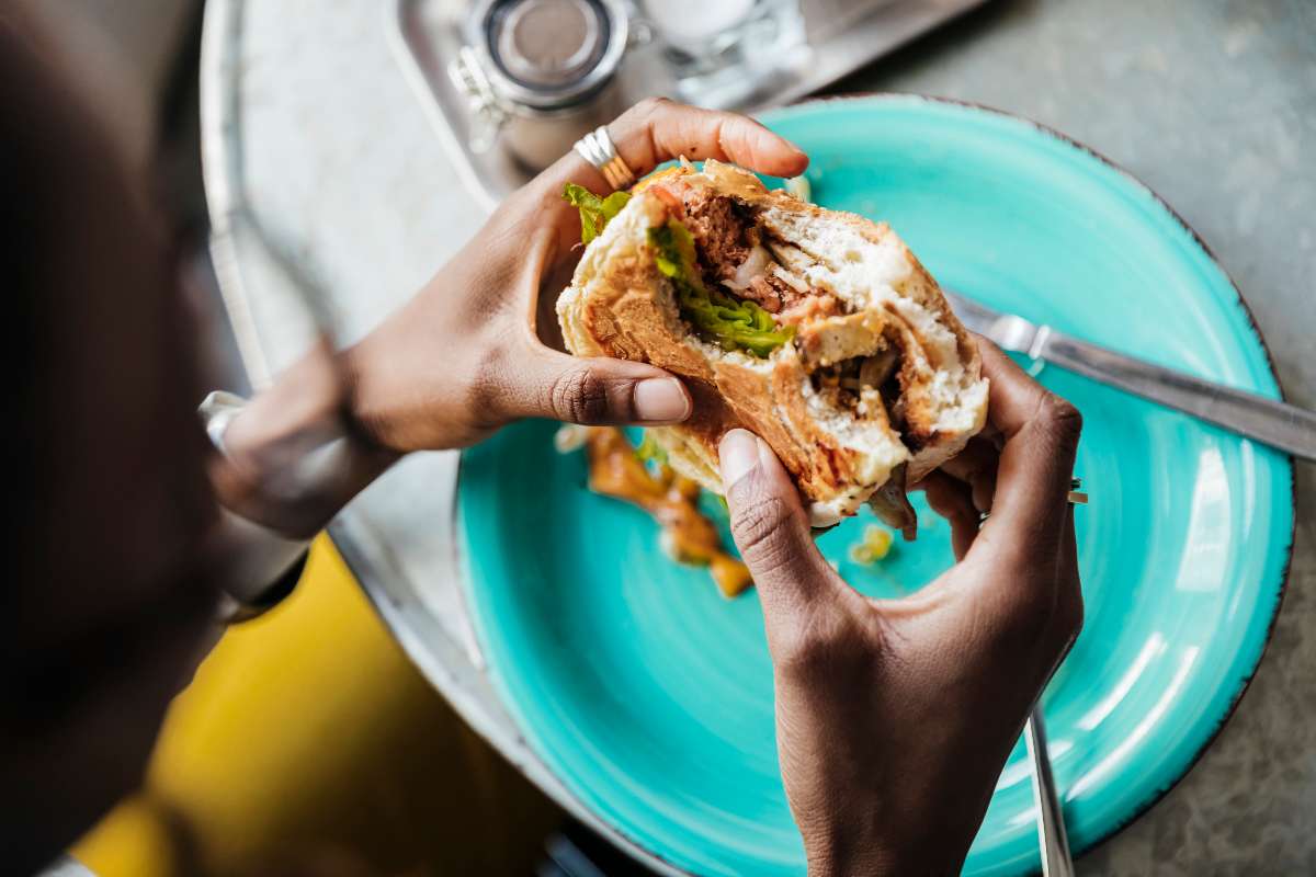 Foto de persona comiendo hamburguesa, en nota de cómo cuidarse de diabetes al comer en restaurantes como El Corral y McDonald's.