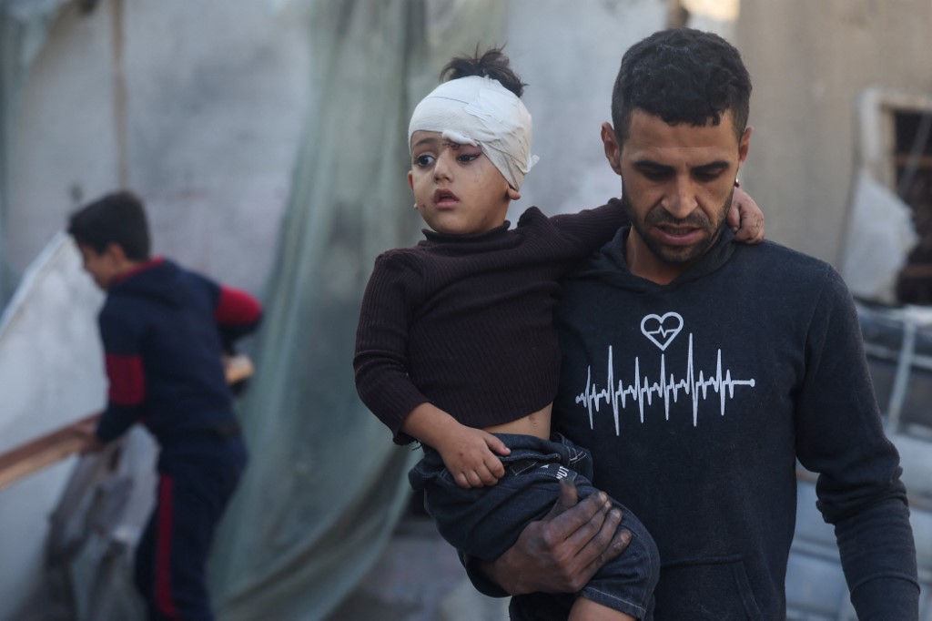 Hombre palestino huye del lugar de un bombardeo con un niño en la Franja de Gaza.