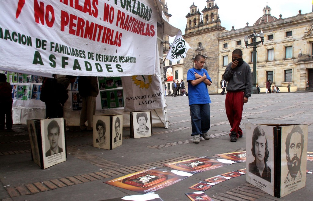 Dos jóvenes observan una exposición en la Plaza de Bolivar, en Bogotá, con cientos de fotografías de ciudadanos colombianos detenidos desaparecidos por fuerzas paramilitares, desde finales de los años 80 hasta la fecha, el 07 de abril de 2005. Segun organizaciones defensoras de los derechos de las víctimas las cifras de éstas ascienden a más de 7 mil personas.