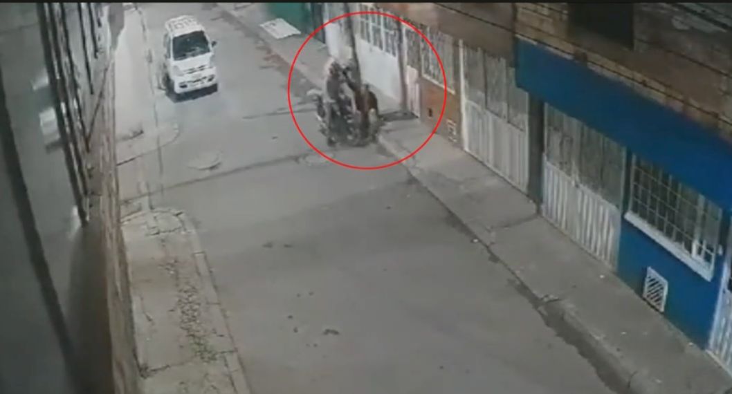 Momento en el que unos delincuentes en Bogotá atracan y golpean a un hombre en una calle. Uno de los ladrones llevaba una maleta de domiciliario