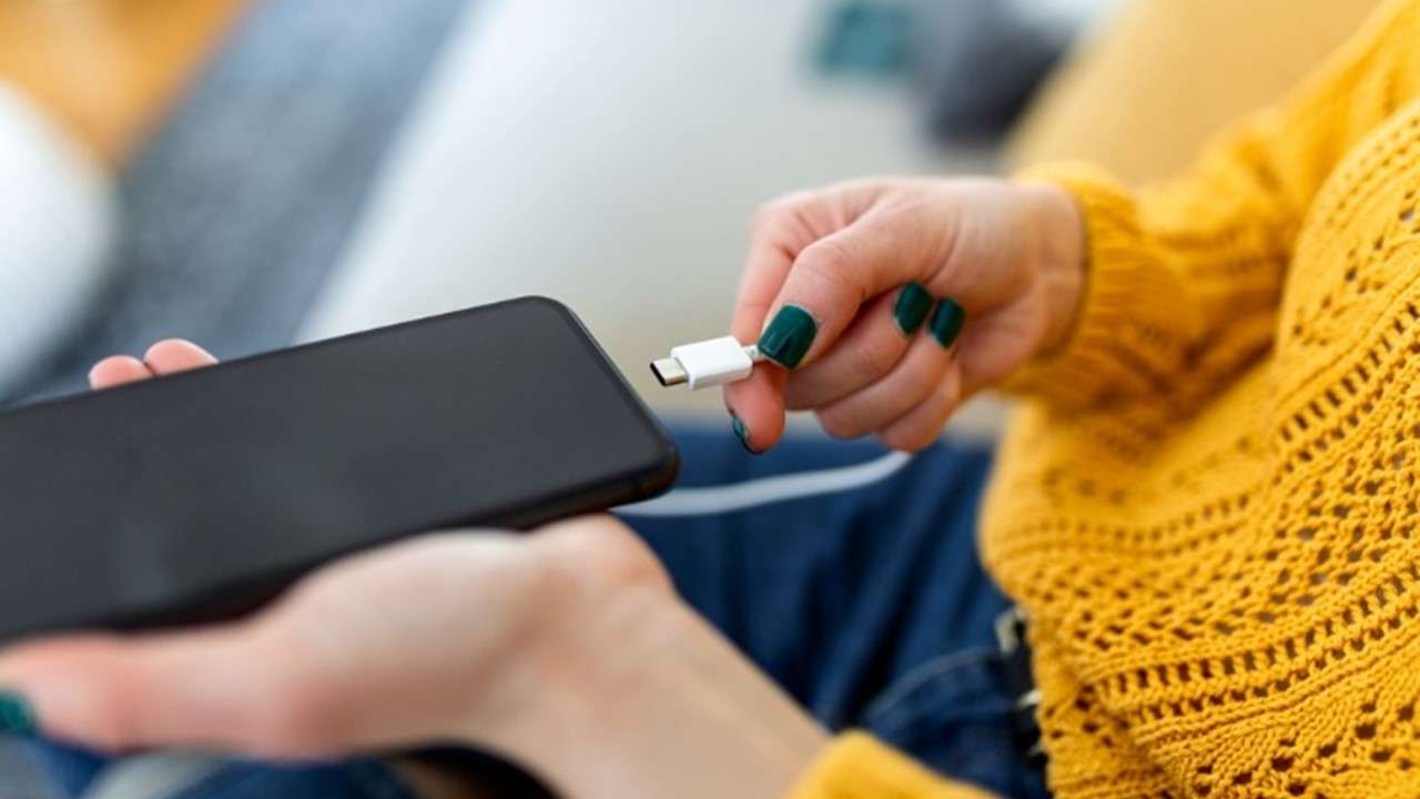 Foto de mujer cargando dispositivo, en nota de cuánto tiempo cargar un celular por primera vez: clave para no dañar la batería