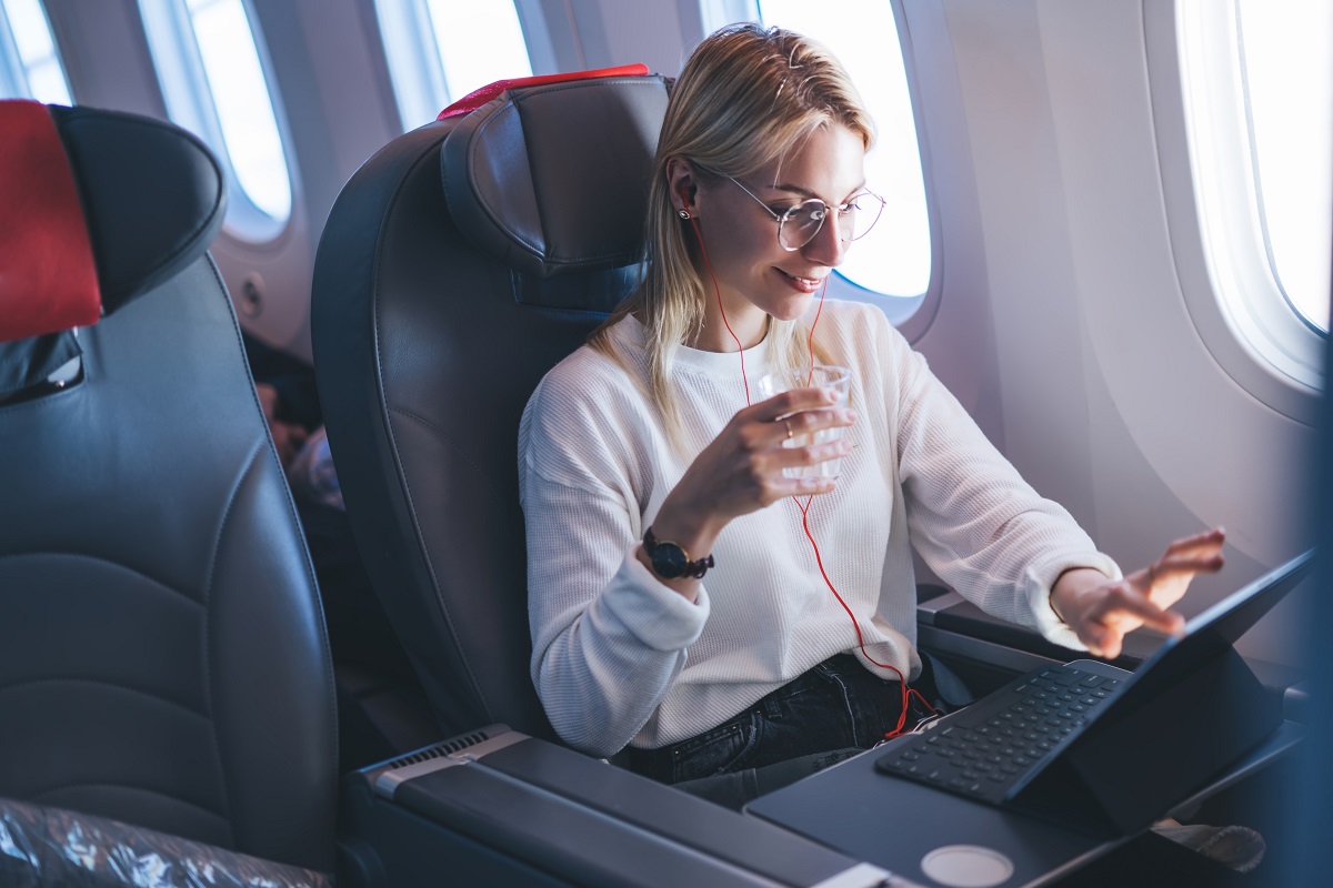 Mujer utilizando computador en un avión, en nota sobre cómo hay Internet en las aeronaves
