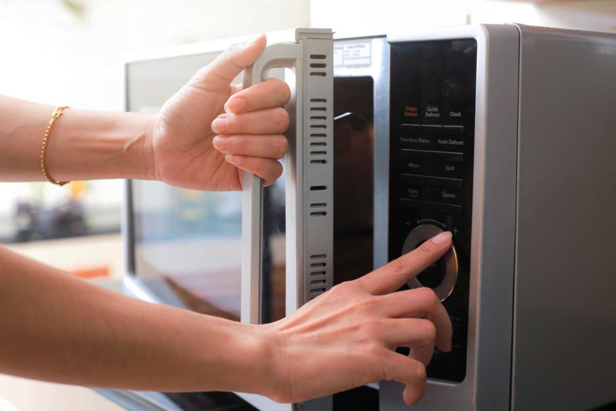Foto de mujer en cocina, en nota de qué bebidas no se deben meter en el microondas.