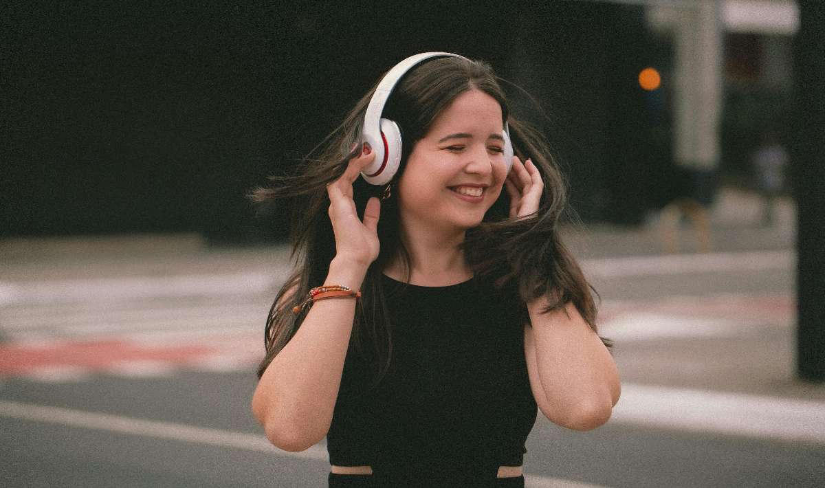 Foto de mujer escuchando auriculares, en nota de cómo se limpian los audífonos inalámbricos sin dañarlos y con pasos muy fáciles
