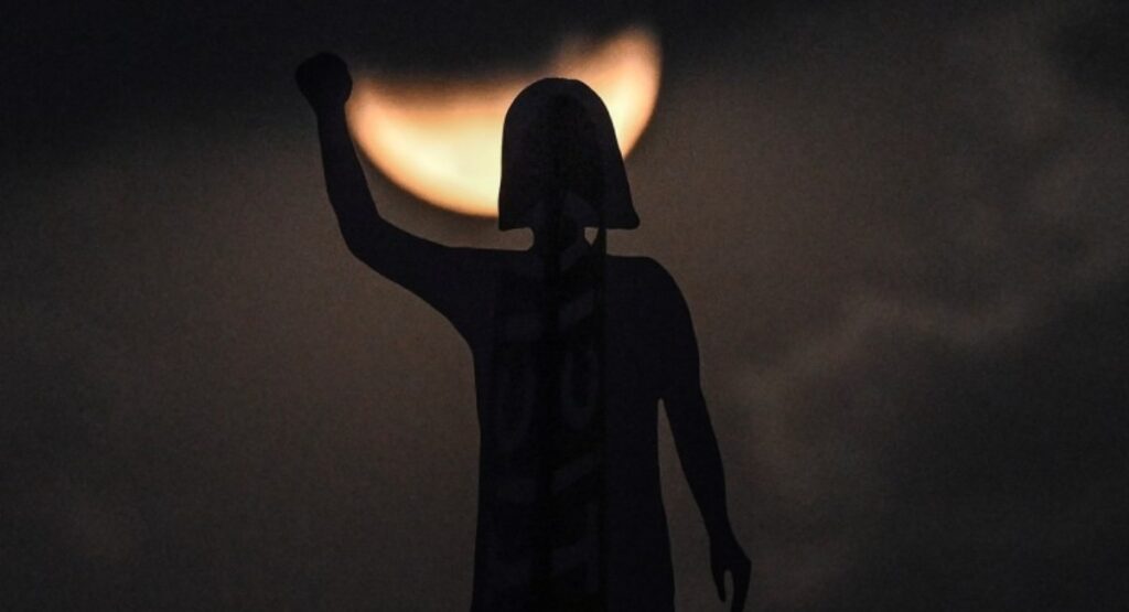 Luna de sangre, se observa tras la silueta del monumento a la Glorieta de las Mujeres que Luchan en la Avenida Reforma de la Ciudad de México / Foto de Yuri CORTEZ / AFP