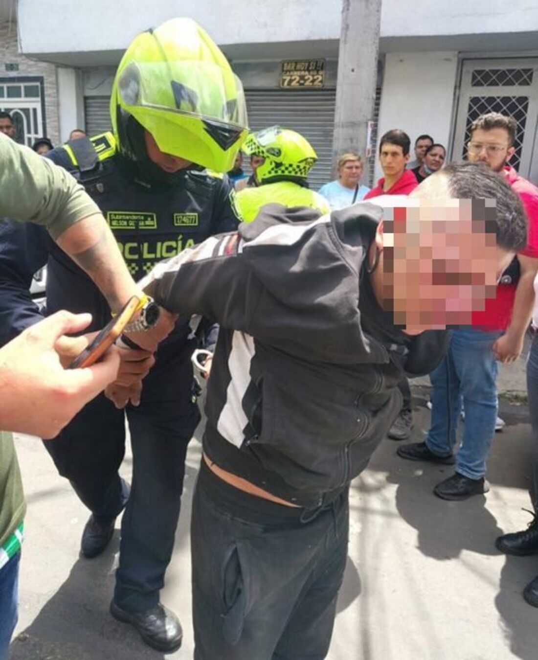 Momento en el que la Policía detiene a un ladrón en Las Ferias, Bogotá, al ser golpeado por ciudadanos que lo vieron hurtando un carro