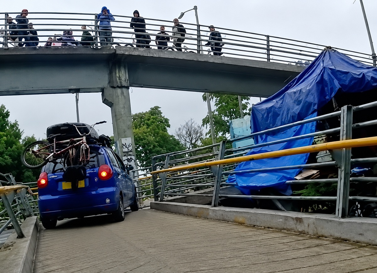 Momento en el que suben un Chevrolet Spark azul en un puente peatonal de Bogotá