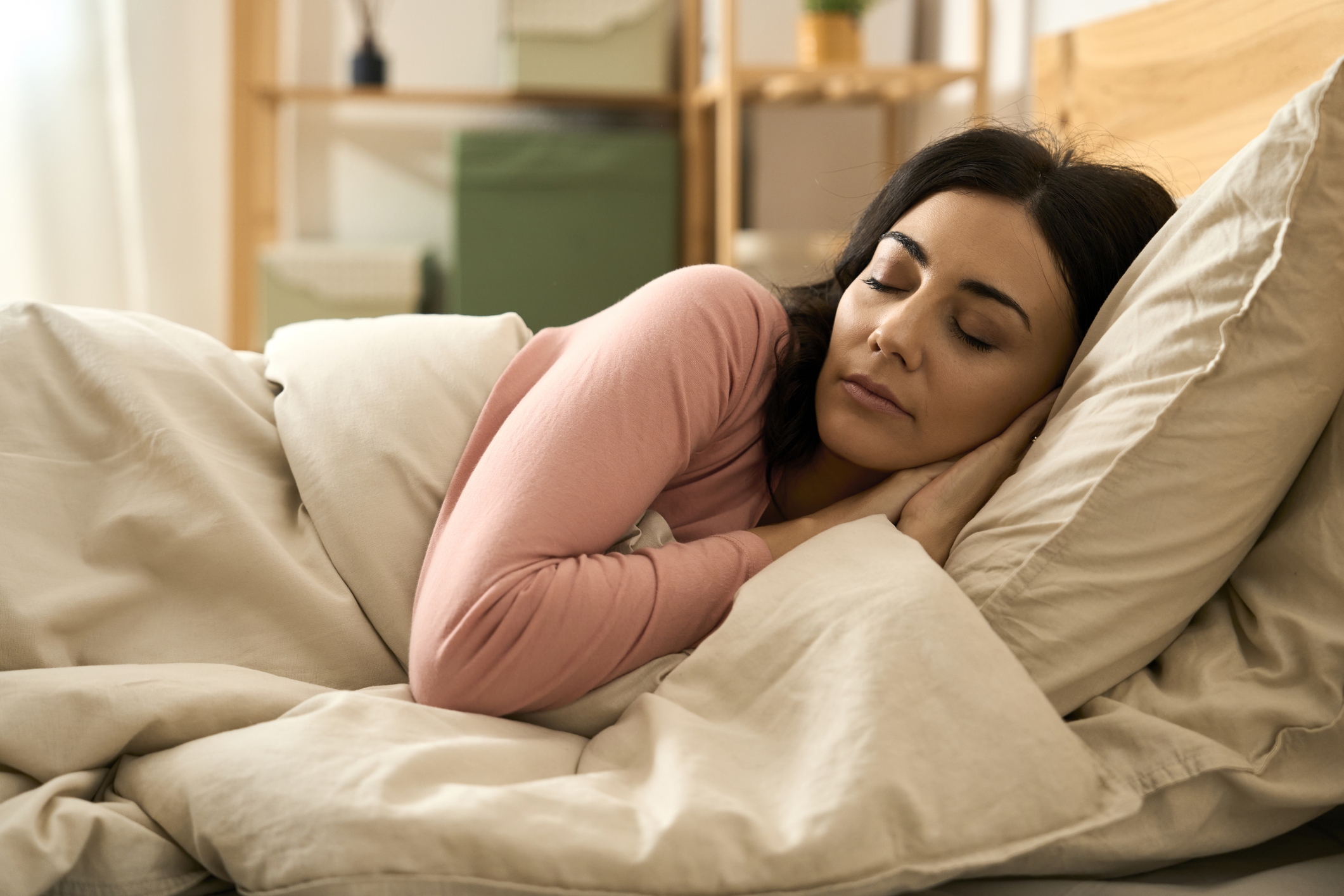 Woman rests peacefully in bed, eyes closed, enjoying comfortable sleep in bedroom