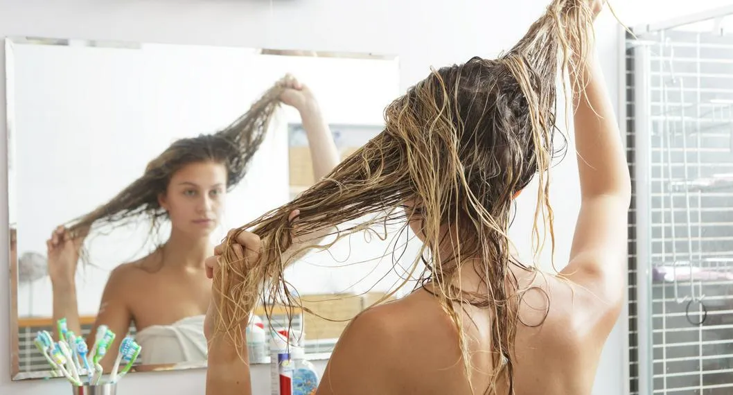 Mujer lavándose el cabello a propósito de cada cuánto debe lavarlo si es seco o graso.