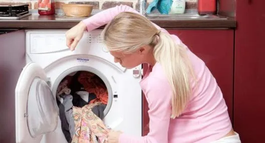 Mujer lavando la ropa a propósito de cómo convertir la lavadora en secadora.