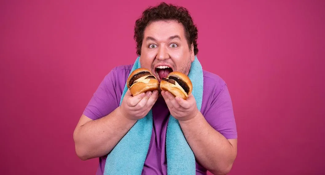 Imagen ilustrativa de un hombre obeso comiendo una hamburguesa.