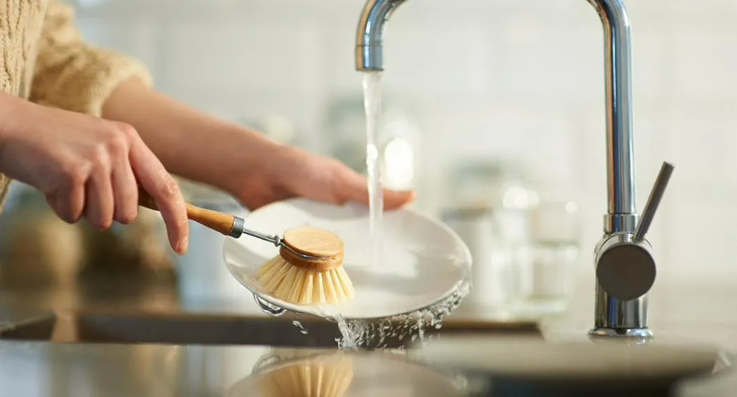 Foto de persona lavando un plato, para ilustrar artículo sobre 3 errores comunes a la hora de lavar platos. 