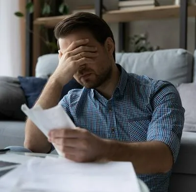 Hombre lamentándose al ver todo lo que tiene que pagar por su tarjeta de crédito. En Colombia, la tasa de usura crecerá considerablemente en abril.
