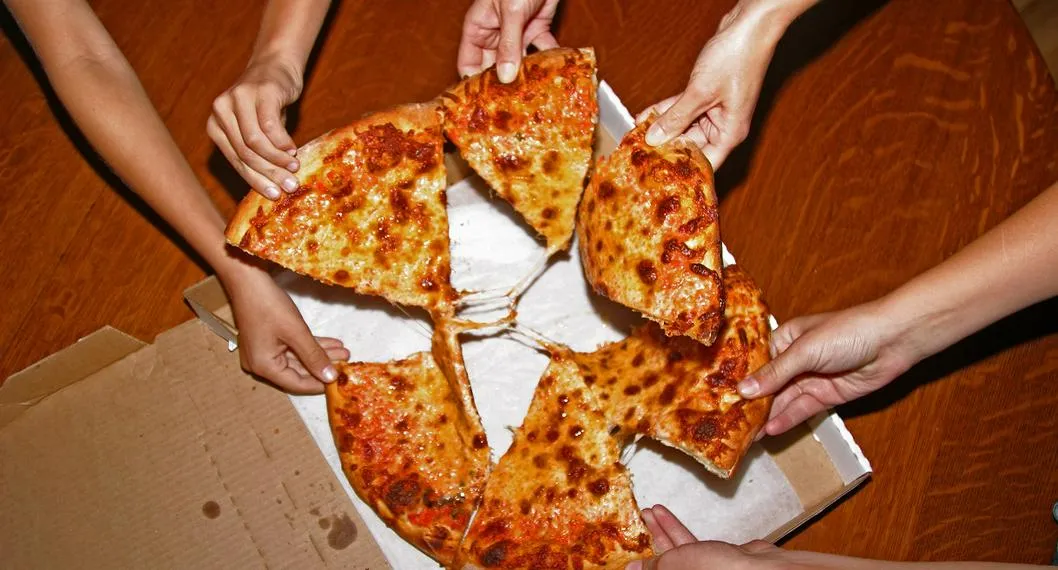 Grupo de amigos comparten una pizza. Descubra cuántas calorías tiene una porción