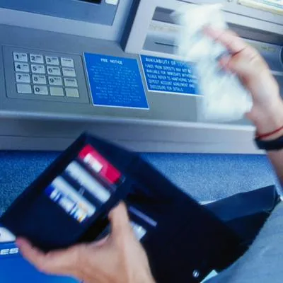 Mujer retirando dinero en cajero ilustra sobre las razones por las que no hay que imprimir el recibo.