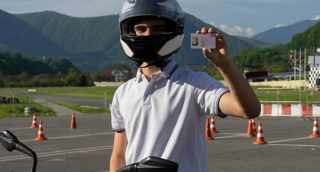 Hombre con casco de moto sostiene licencia de conducción ilustra nota sobre renovación de este documento.