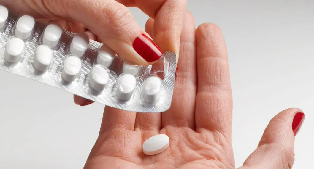 Mano de una mujer sacando una pastilla ilustra nota sobre los opioides y sus efectos.